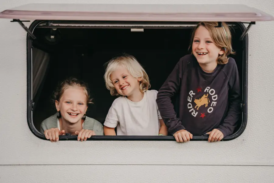 kindjes in caravan hangen uit het raam en zijn blij
