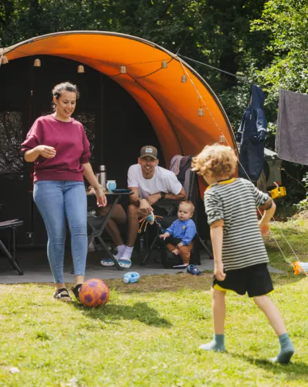 Moeder zoon bvader voetballen bij de tent en caravan