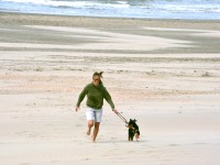 girl with sunglasses running with dog at the beach.jpg